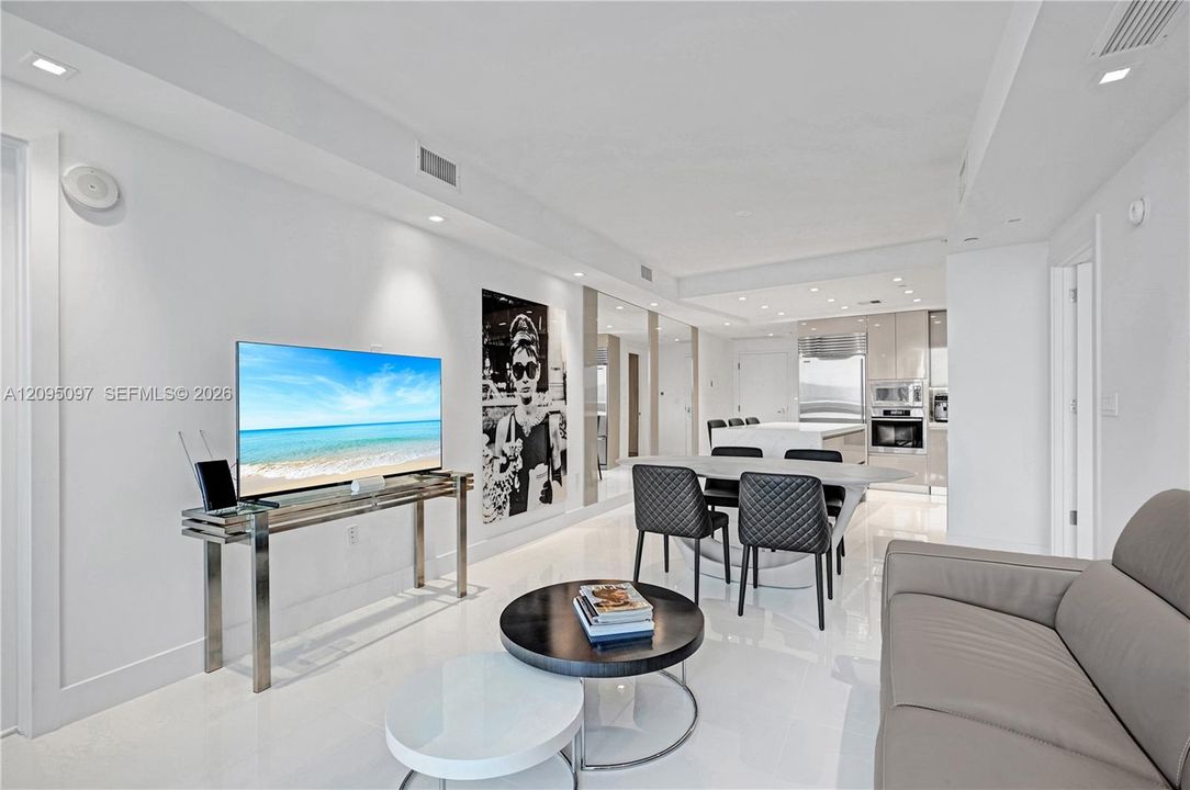 Open-concept living space featuring high-gloss flooring, recessed lighting, integrated ceiling speakers, and kitchen cabinetry with a reflective finish
