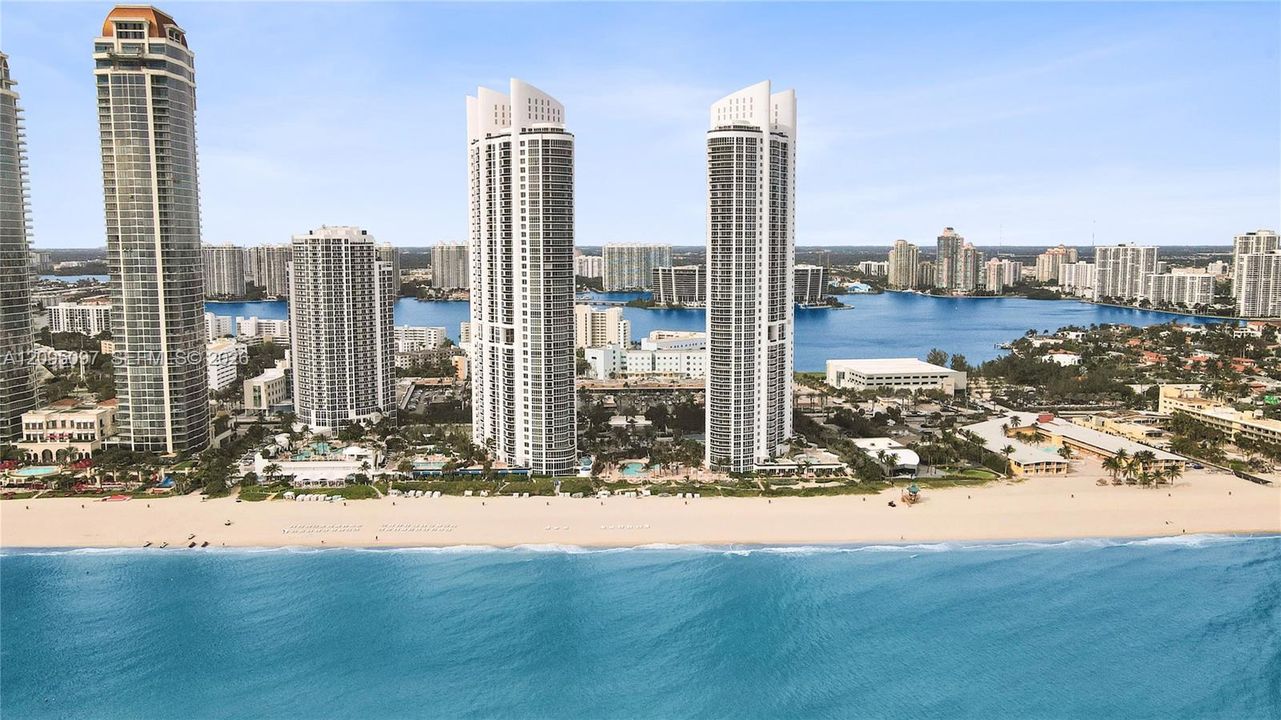 High-rise residential towers featuring glass-facade architecture, direct sandy shoreline access, and proximity to expansive waterfront scenery