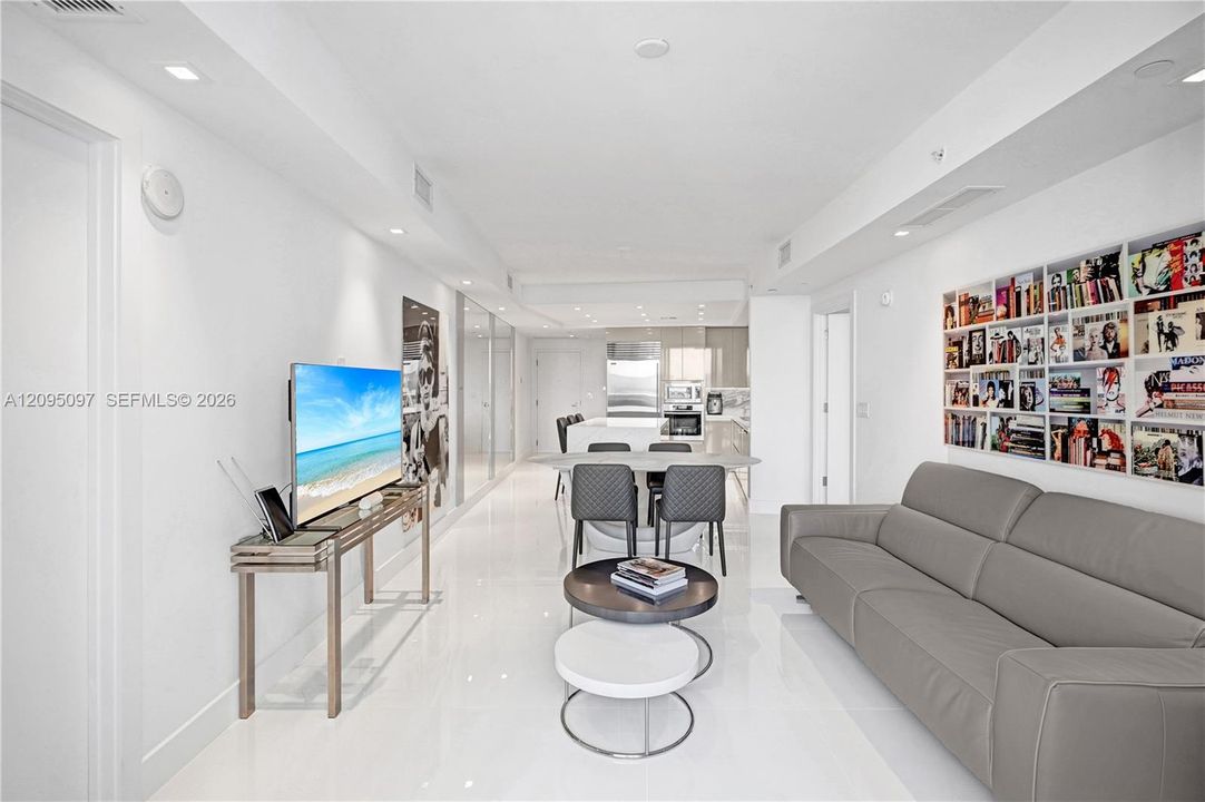 Open-concept interior featuring large-format polished tile flooring, recessed ceiling lighting, and custom built-in recessed shelving