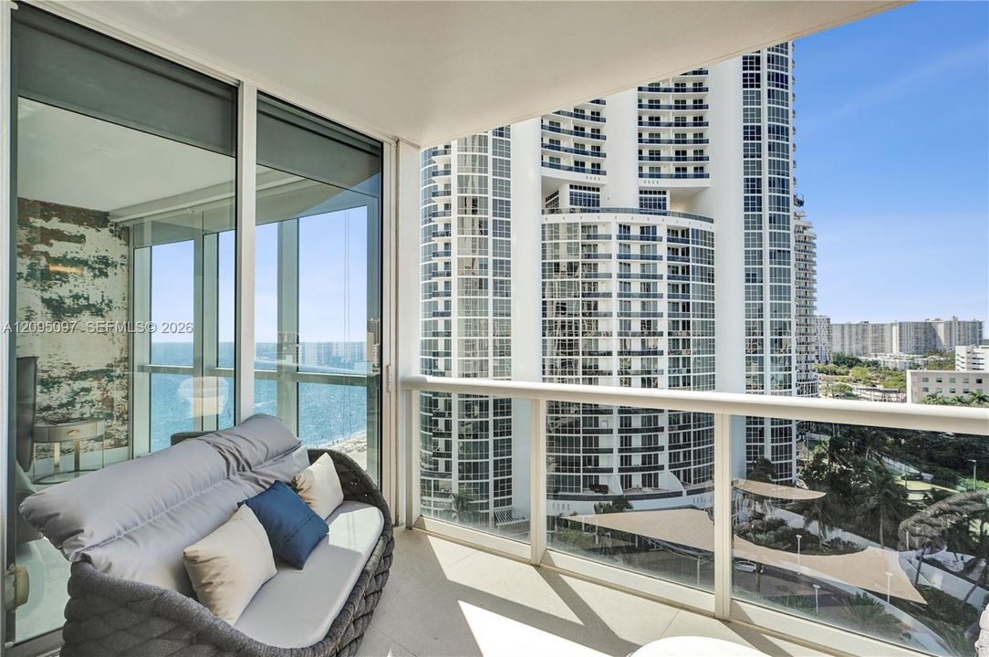 Private balcony featuring expansive floor-to-ceiling glass wall, sleek glass-panel railing, and durable tile flooring