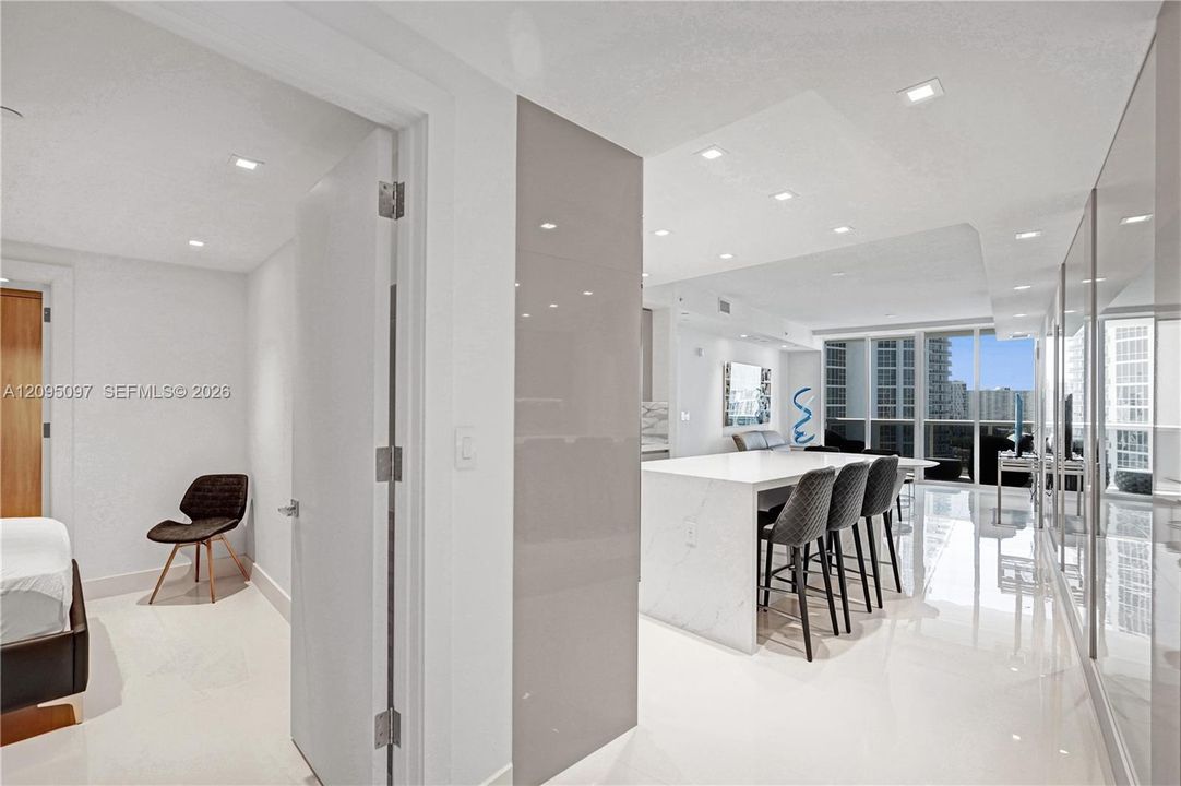 Kitchen island with waterfall countertop, recessed ceiling lighting, glossy wall paneling, polished flooring, and floor-to-ceiling windows