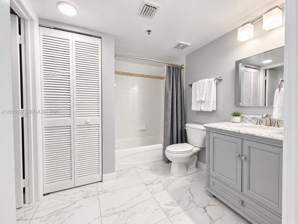 Remodeled bathroom with grey vanity and tub/shower combo