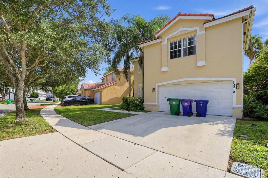 Two-story exterior featuring a stucco facade, tile roof, concrete driveway, and attached two-car garage