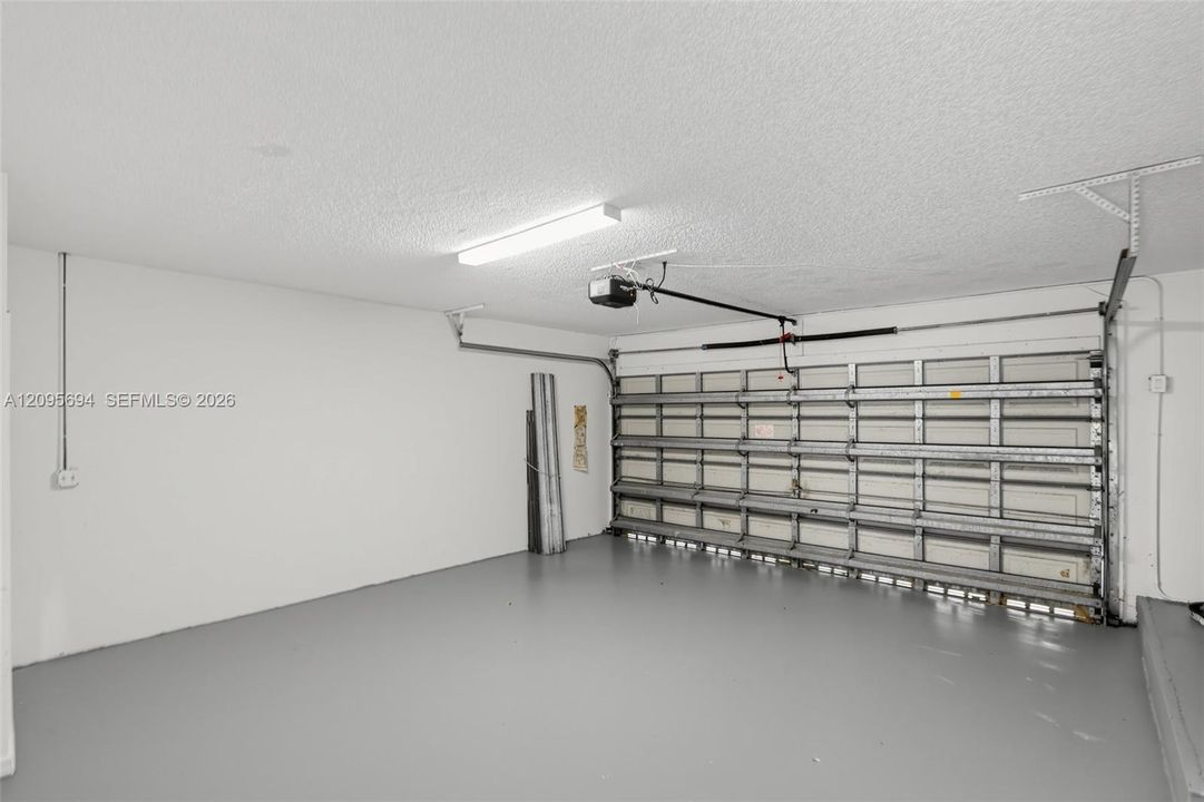 Attached garage featuring finished painted walls, a painted concrete floor, a multi-panel steel garage door, and a ceiling-mounted light fixture