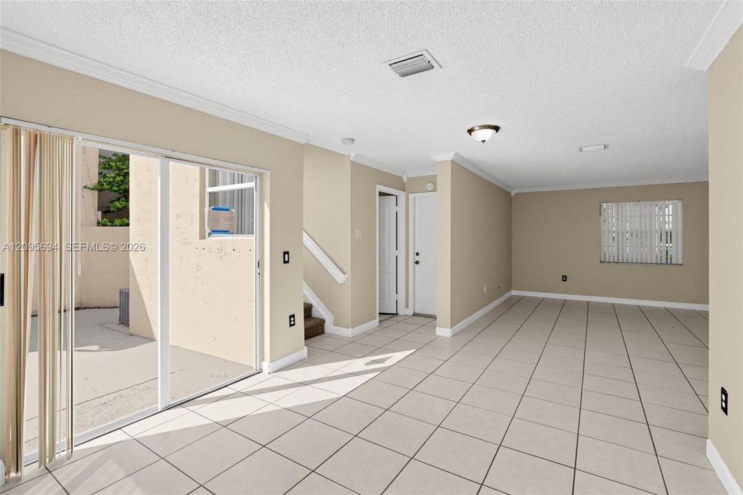 Interior space featuring tile flooring, crown molding, sliding glass patio doors, and natural light exposure
