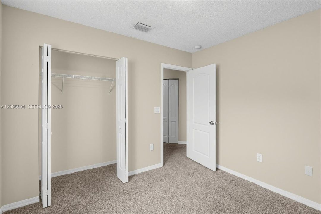 Neutral-toned interior room with carpeted flooring, a reach-in closet with bifold doors, and a paneled interior door