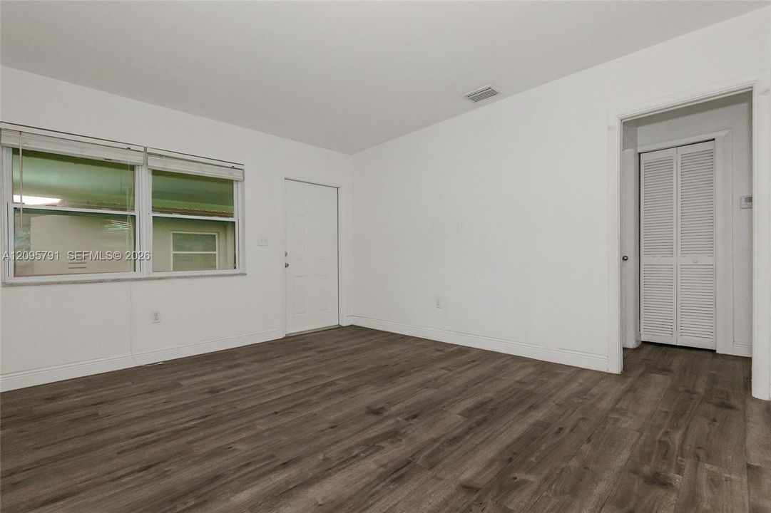 The view from the windows on the side wall of the living room back toward the front windows and entry door. The open walkthru is to the bathroom and bedroom areas.