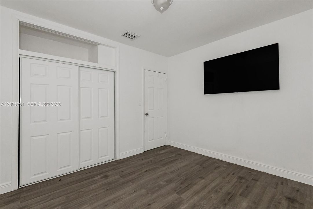 View in the bedroom with the double sliding closet doors and storage above. The entry door is in the corner.