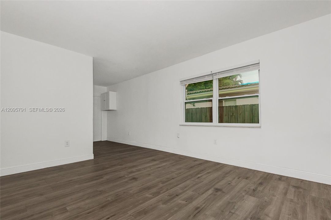 Another view of the living room showing a spacious wall, and windows to brighten up the room. Great area to place a sofa and chairs.