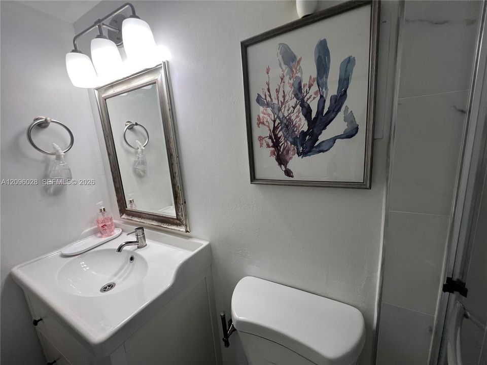 Vanity featuring a white integrated sink, polished metal faucet, three-light overhead fixture, and rectangular mirror