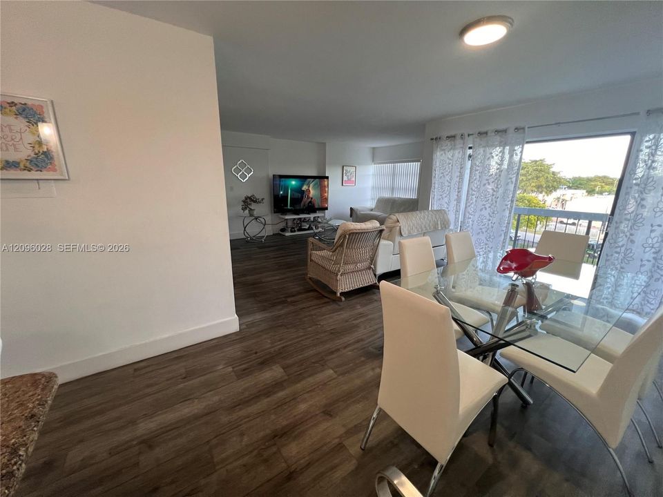 Open-concept interior featuring wood-finish flooring, sliding glass balcony doors, and recessed ceiling lighting
