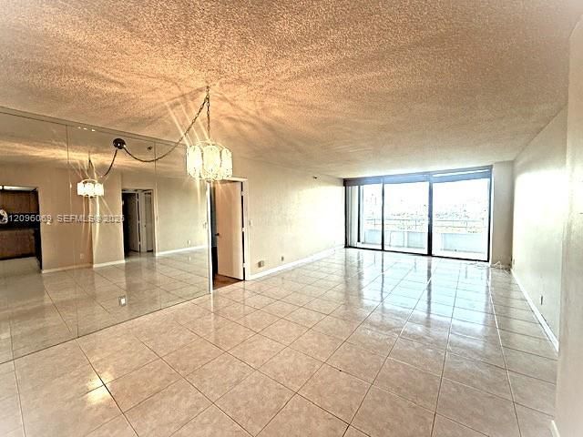 Interior space featuring tile flooring, floor-to-ceiling mirrored wall paneling, multi-panel sliding glass doors, and a decorative chandelier