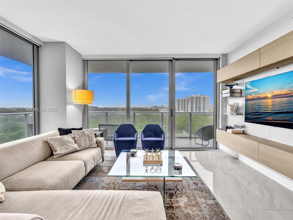 Floor-to-ceiling glass sliding doors, polished tile flooring, built-in wall-mounted cabinetry with wood-finish paneling, and an expansive balcony