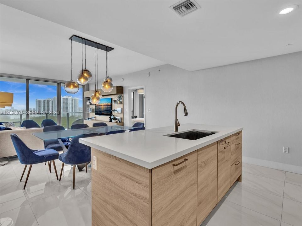 Kitchen island with wood-finish cabinetry, white countertop, and under-mount sink featuring a gooseneck faucet