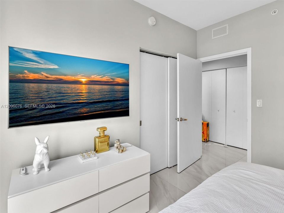 Neutral wall palette, polished stone-finish flooring, and multiple sets of white bi-fold closet doors