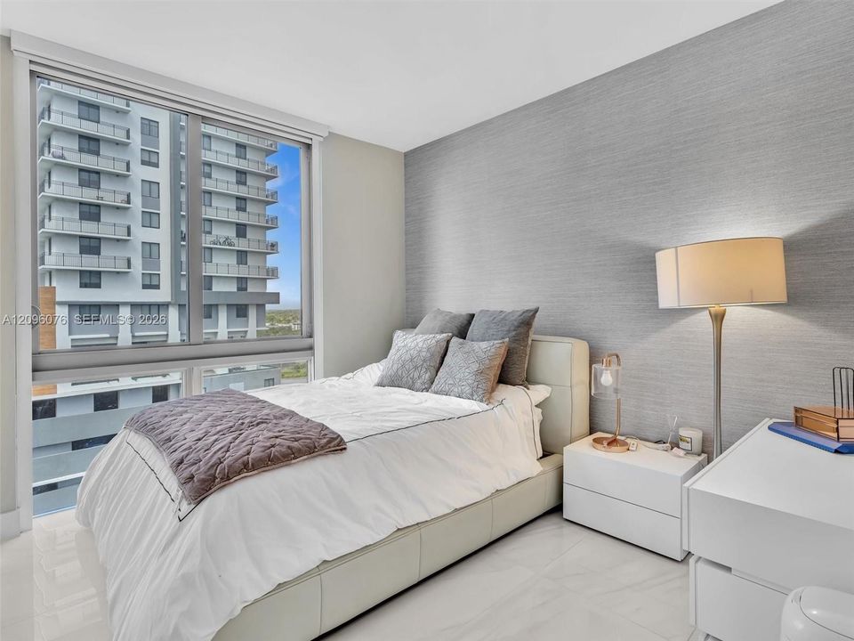 Floor-to-ceiling windows, textured accent wall, and polished tile flooring
