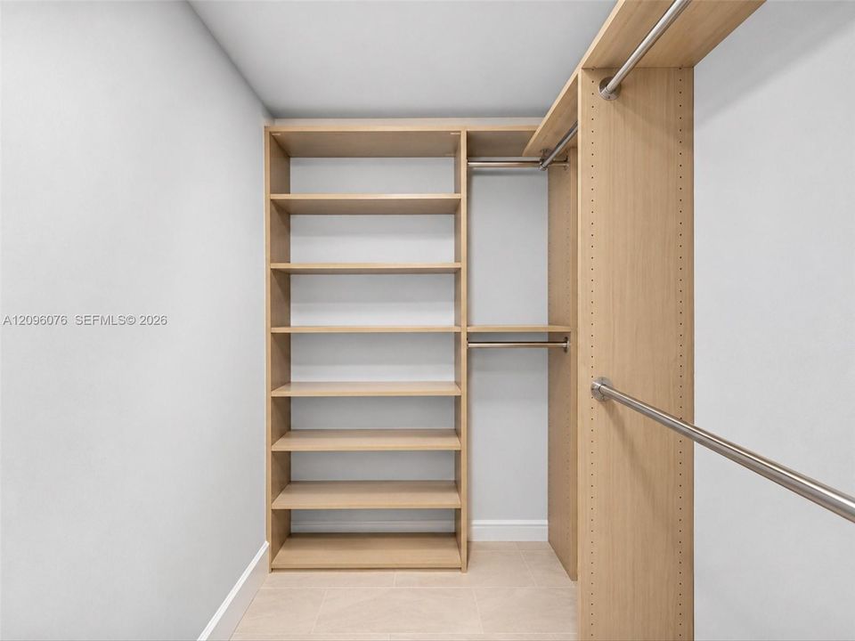 Custom built-in storage featuring light wood-finish shelving, integrated metallic hanging rods, and adjustable hardware
