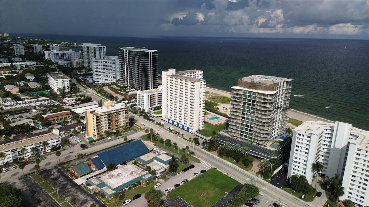 Aerial perspective of coastal high-rise structures featuring glass-paneled balconies and immediate proximity to the Atlantic Ocean shoreline