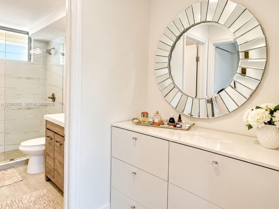 Stylish outer vanity area featuring an elegant round accent mirror and modern sink basin located just outside the main bathroom.