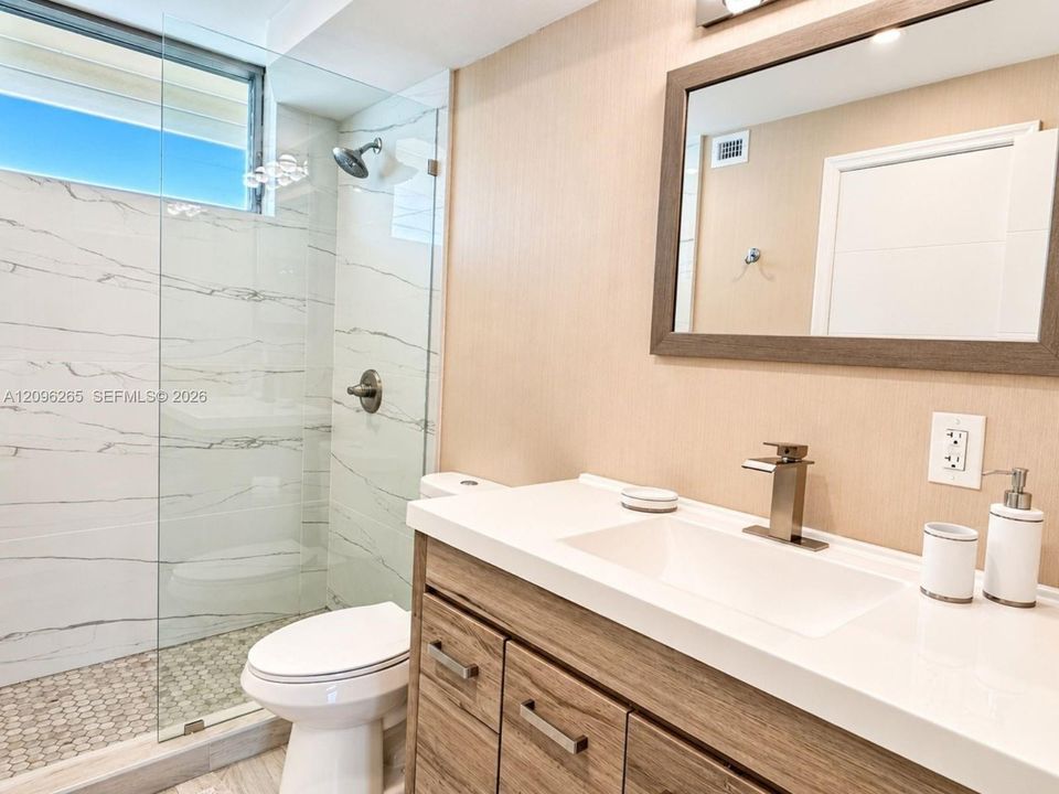 Renovated primary bathroom featuring a modern vanity with framed mirror and updated finishes.