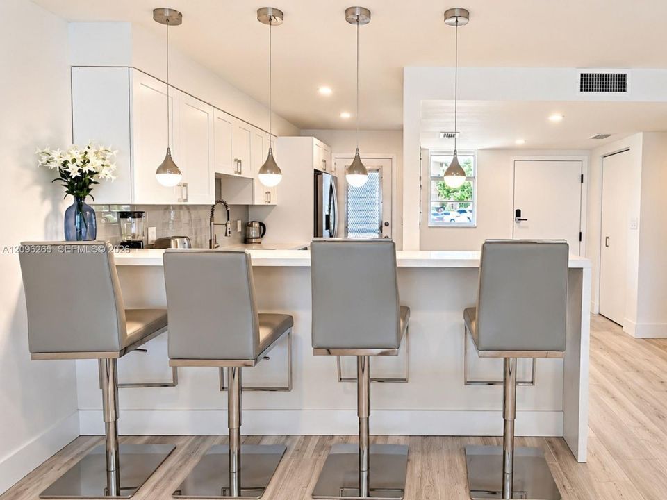 Alternate view of the renovated kitchen featuring breakfast bar counter seating and modern lighting.
