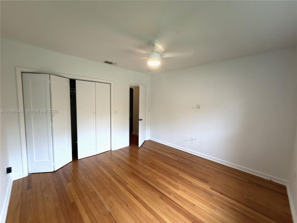 Front bedroom with bright sunny windows, hard wood floors, and large closet