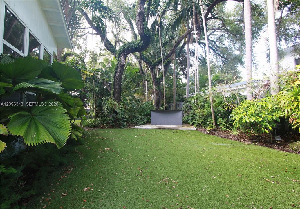 Landscaped gated yard with turf and built in bar for bbq