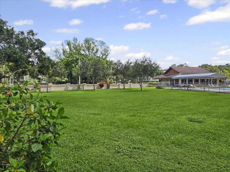 Expansive lawn featuring perimeter wall enclosure, mature landscaping, and a covered pavilion structure