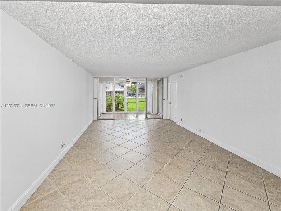 Neutral-toned tile flooring, textured ceiling, and sliding glass doors with exterior access