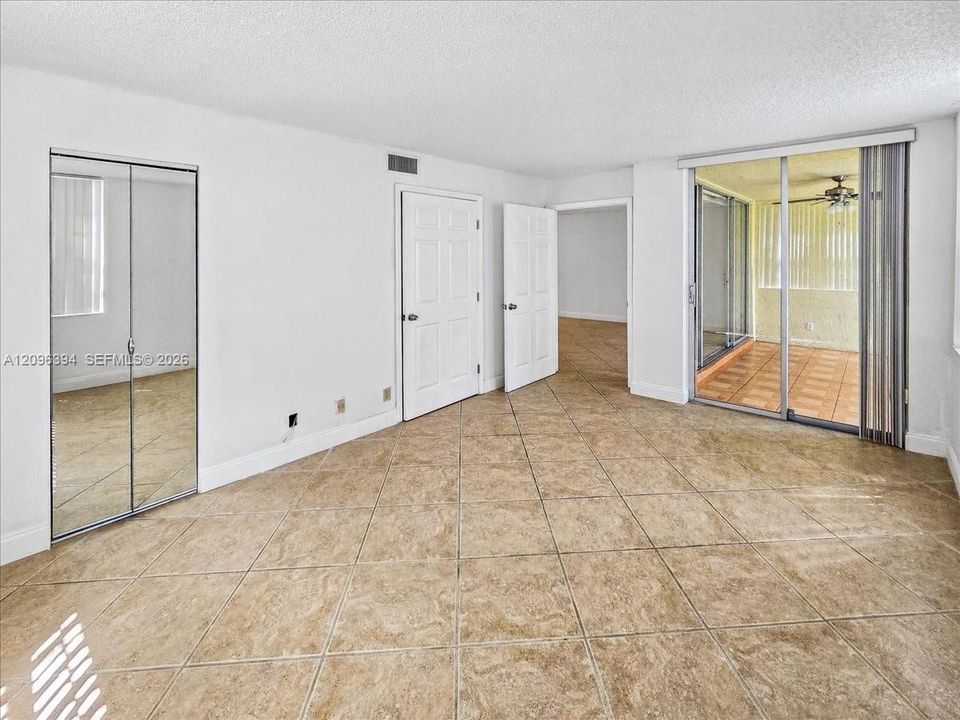 Interior space featuring diagonal ceramic tile flooring, mirrored sliding closet doors, and a sliding glass door providing access to a screened enclosure