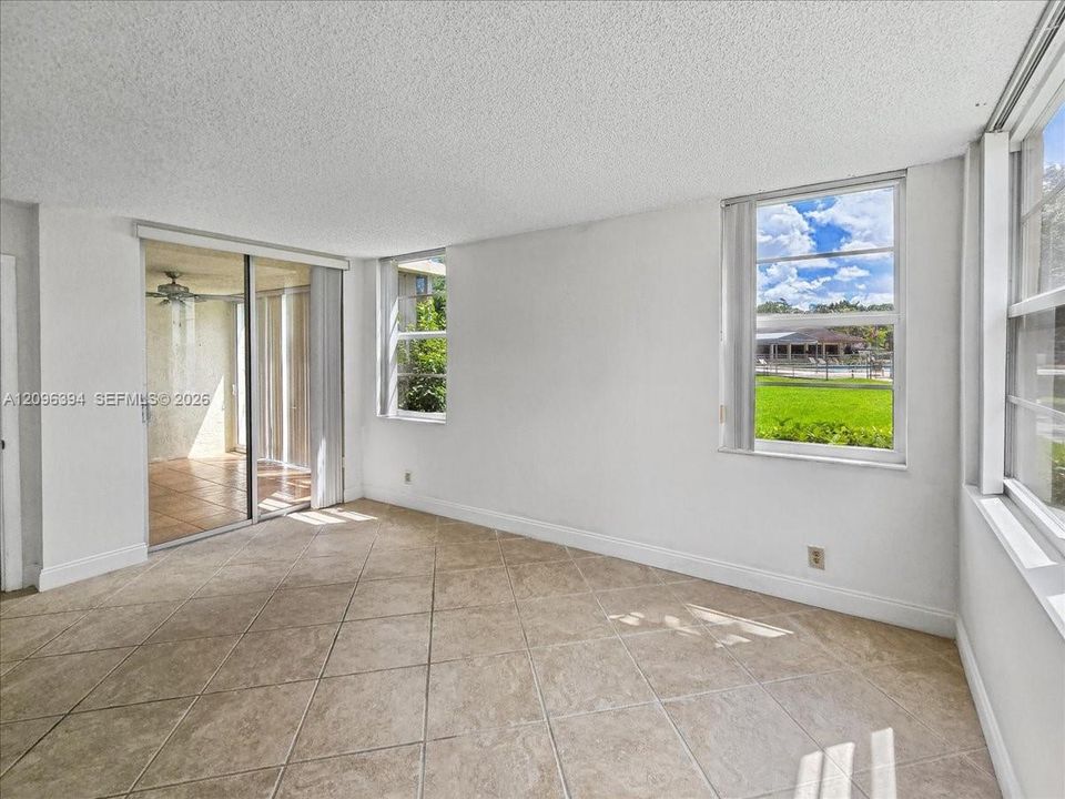 Living area featuring neutral-tone tile flooring, sliding glass doors, and multiple windows providing natural light