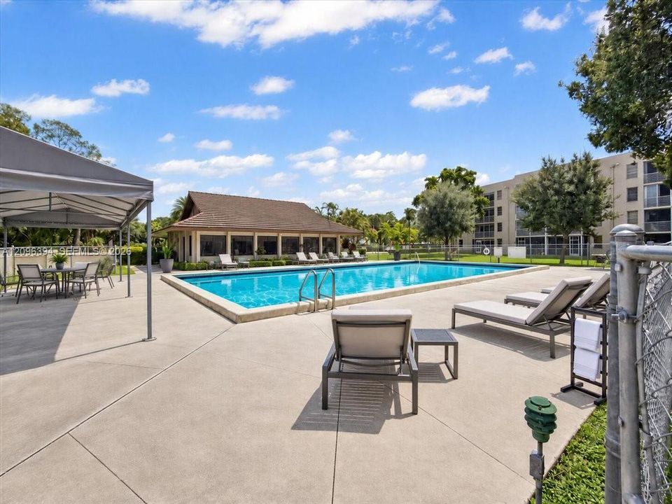 Outdoor swimming pool featuring a concrete deck, covered pavilion, and metal perimeter fencing