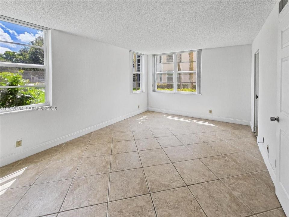 Interior space featuring neutral-toned tile flooring, textured ceilings, and dual-aspect windows