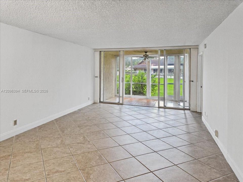 Open-concept interior featuring large-format diagonal tile flooring, textured ceiling, and floor-to-ceiling glass sliding doors opening to a covered patio