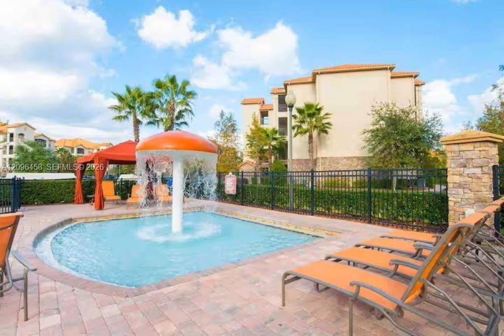Community pool area featuring a mushroom-shaped water feature, stone-finished perimeter wall, and paver decking