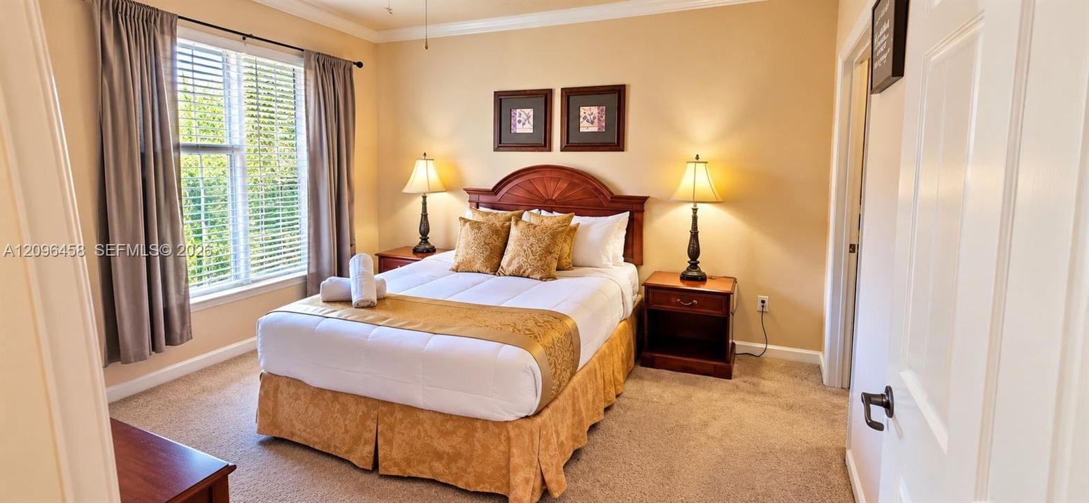 Carpeted bedroom featuring neutral wall paint, crown molding, and a multi-pane window with adjustable blinds
