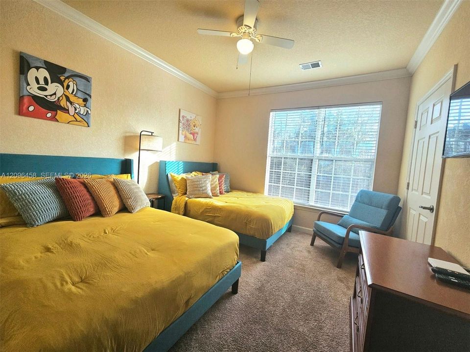 Neutral-toned room featuring crown molding, carpeting, a ceiling fan with integrated lighting, and a multi-pane window