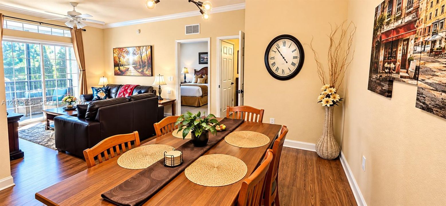 Wood-finish flooring, sliding glass door with transom window, ceiling fan, and crown molding