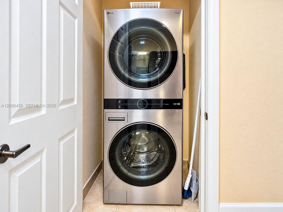 Stacked stainless steel front-load washer and dryer unit with integrated digital control panels
