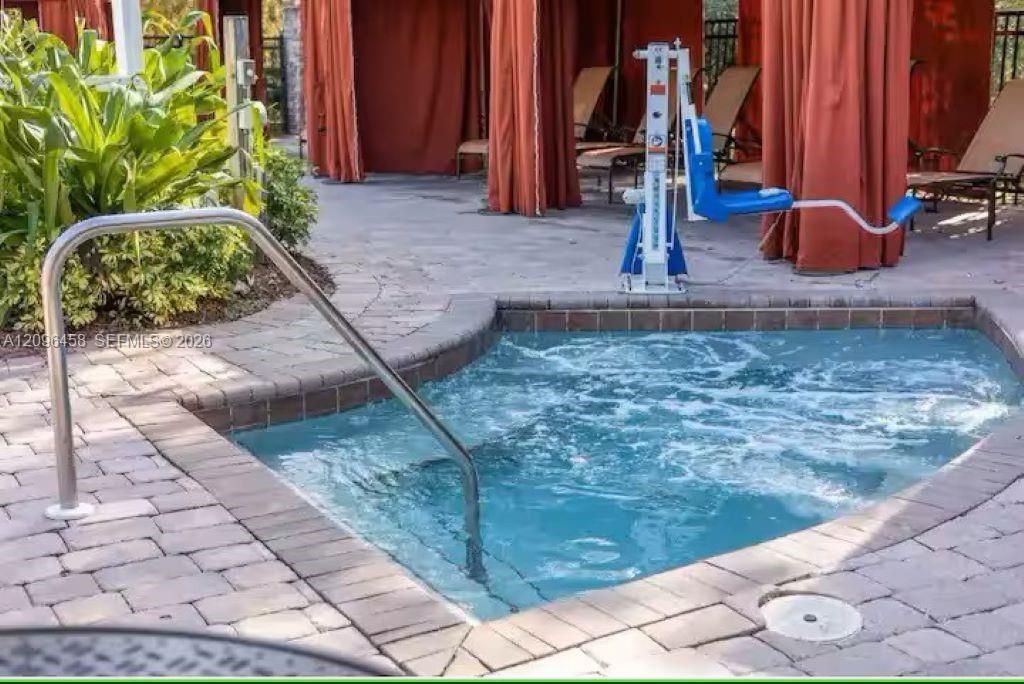 In-ground spa with stone paver surround and integrated stainless steel handrail