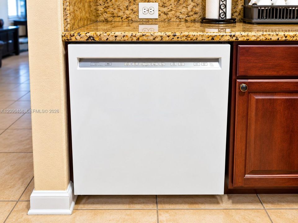 Built-in white dishwasher featuring a front-facing control panel, complemented by stone-finish countertops and dark wood-toned cabinetry