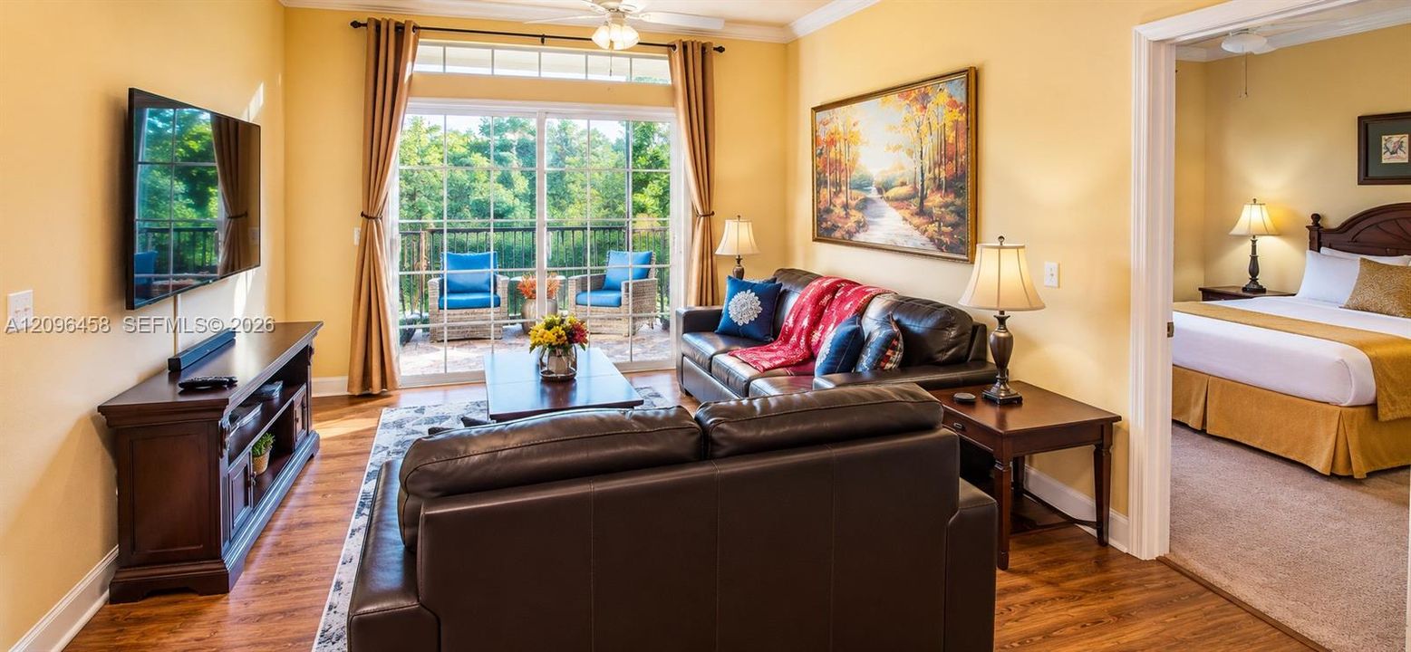 Living area featuring wood-finish flooring, sliding glass doors with transom windows, and crown molding