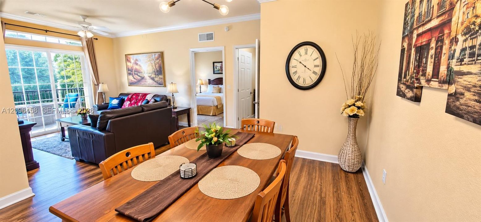 Wood-finish flooring, sliding glass door with transom window, multi-arm chandelier, and crown molding