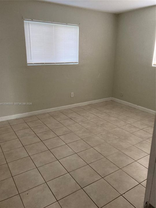 Neutral-toned room featuring ceramic tile flooring, neutral wall paint, and horizontal window blinds