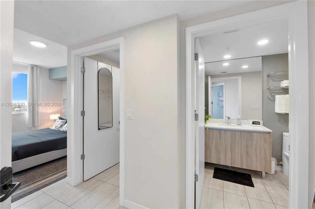Bathroom featuring a wood-finish vanity with a light-toned countertop, recessed ceiling lighting, and tile flooring