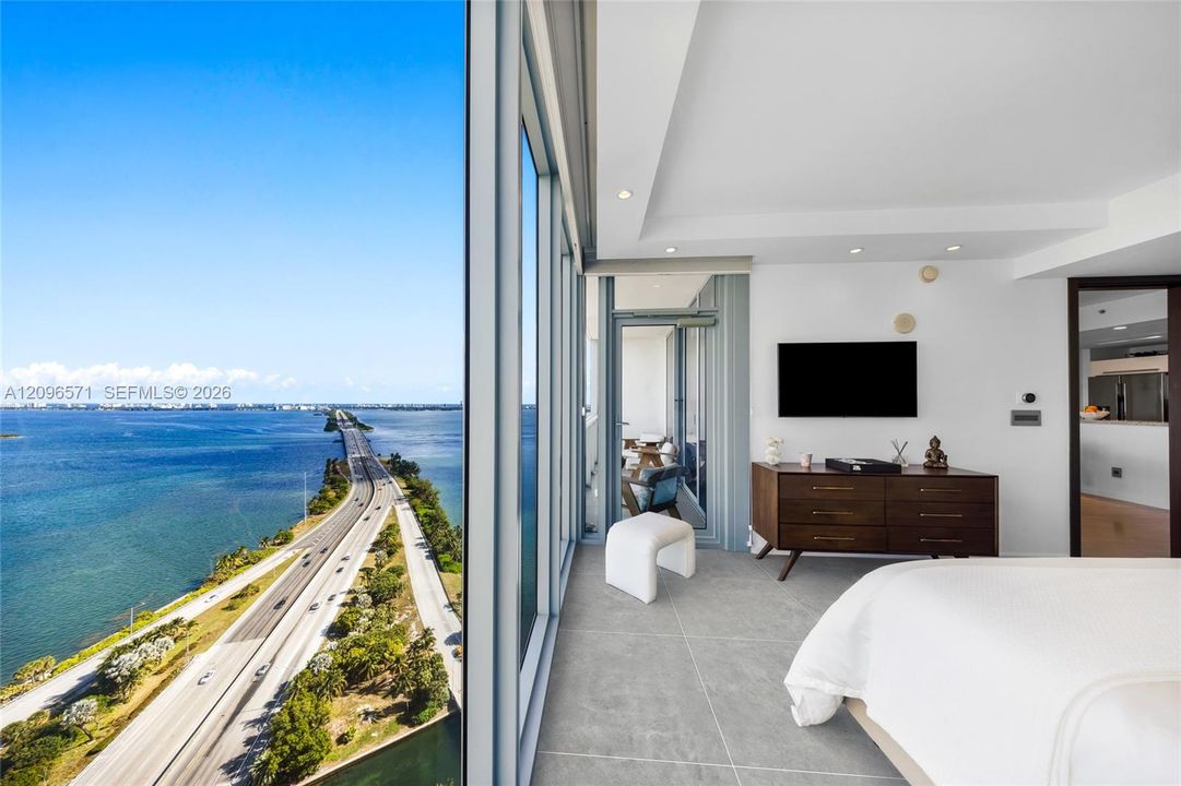 Floor-to-ceiling glass wall, large-format tile flooring, recessed ceiling lighting, and access to an exterior balcony