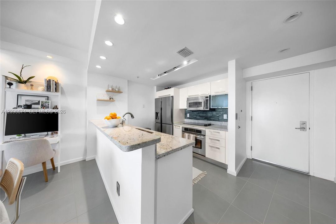 Kitchen featuring stone countertops, stainless steel appliances, white cabinetry, recessed lighting, and tile flooring