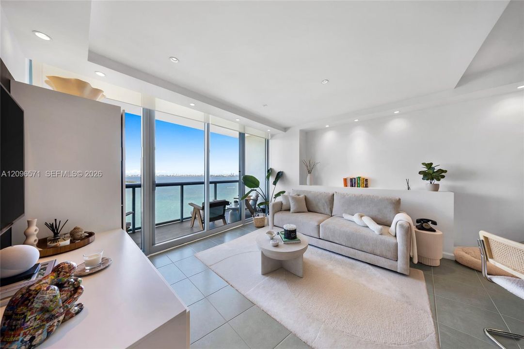 Living area featuring tile flooring, recessed lighting, built-in recessed wall shelving, and floor-to-ceiling glass sliding doors opening to a balcony