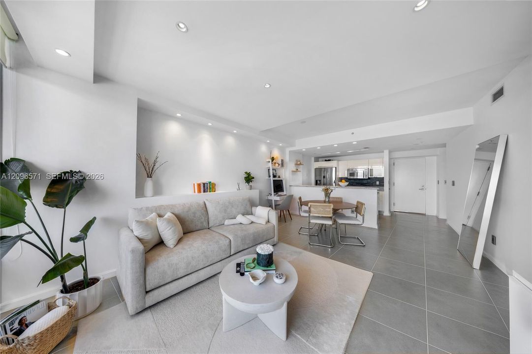 Open-concept interior featuring large-format tile flooring, recessed ceiling lighting, and a built-in wall niche with integrated accent lighting