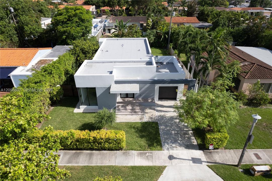 Modern exterior featuring a flat roofline, smooth stucco finish, single-car garage, and a paved driveway